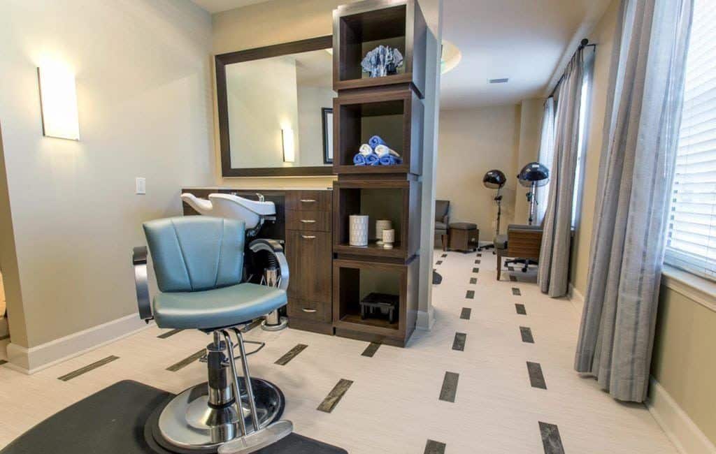 Salon chair with washing sink and hairdryers in the background